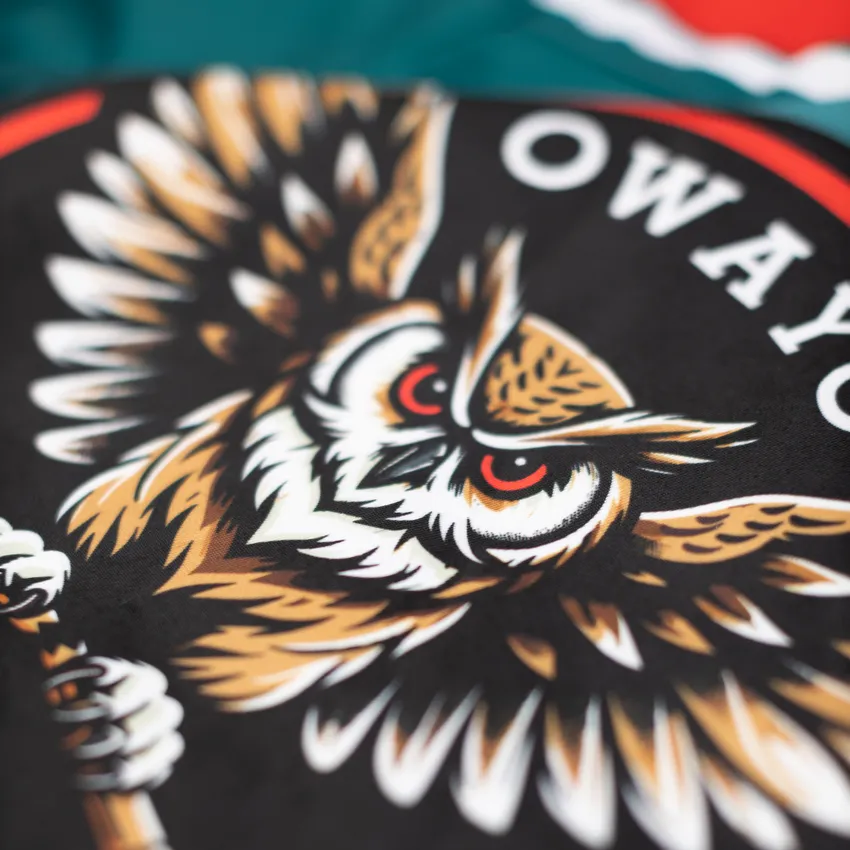 Close-up of a design featuring a stylized, aggressive owl depicted on a black background.