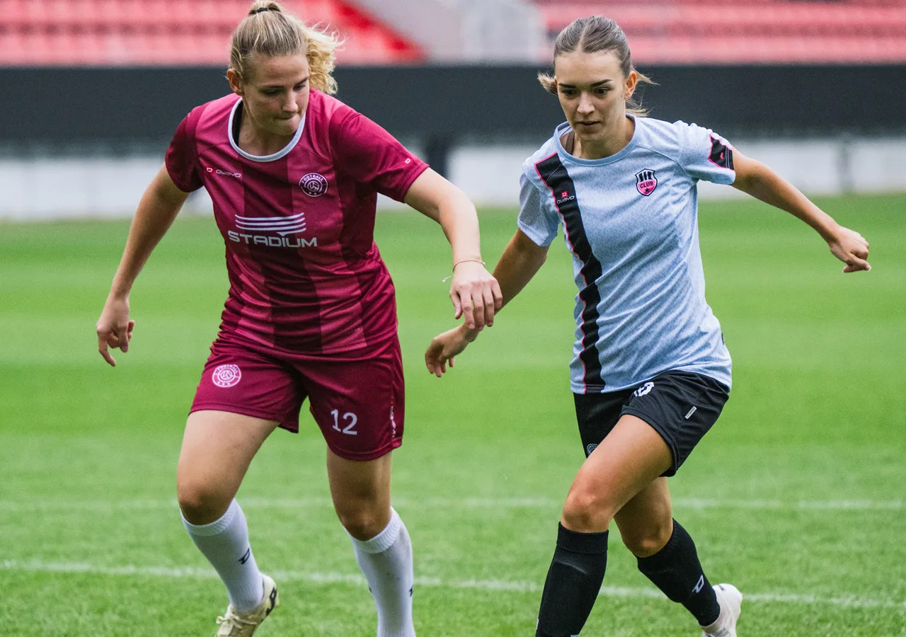 Two female soccer players in colorful jerseys interacting on a grass field.