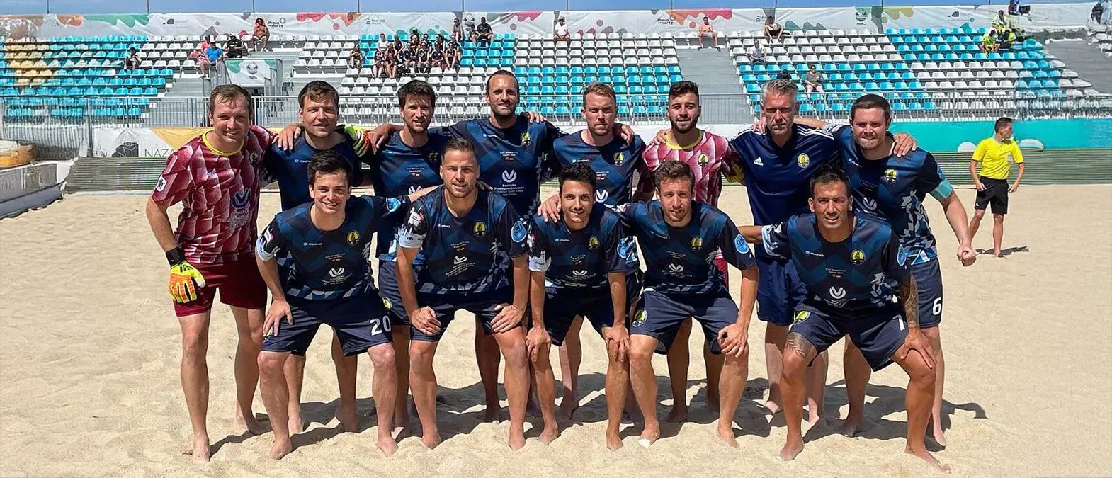 A football team poses on a sand court in customized sportswear made by owayo.