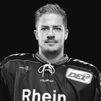 A man wearing a black hockey jersey with the owayo logo on the chest and the word 'Rhein' on the front.