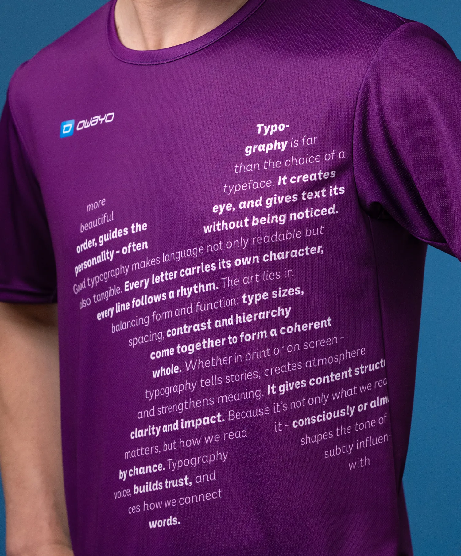 A close-up of a purple sports shirt featuring various typographic texts on the front, worn by a model.