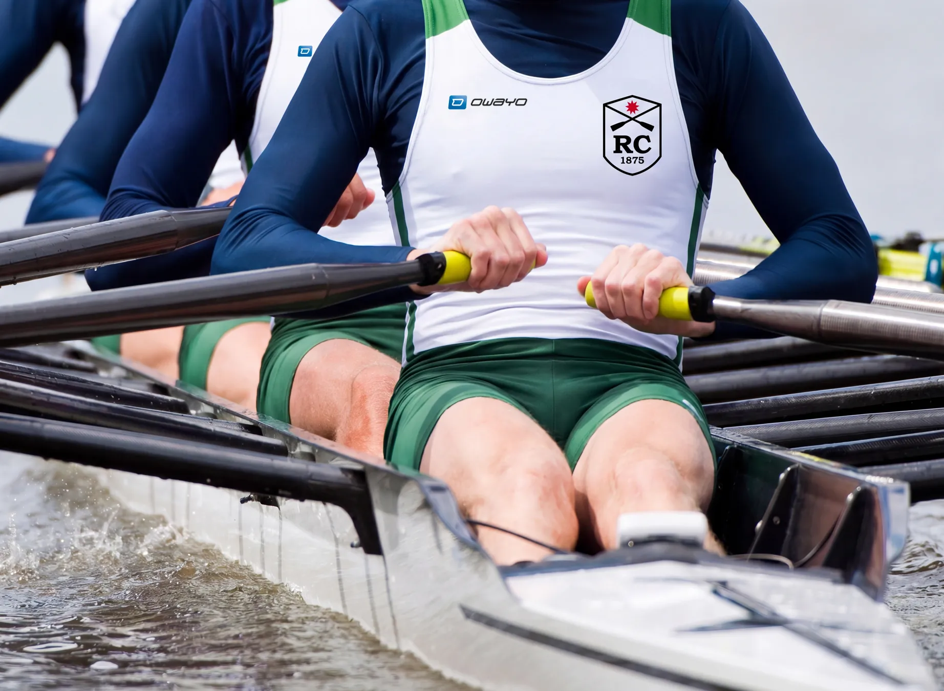 A group of rowers in customized sportswear, actively rowing in a boat.