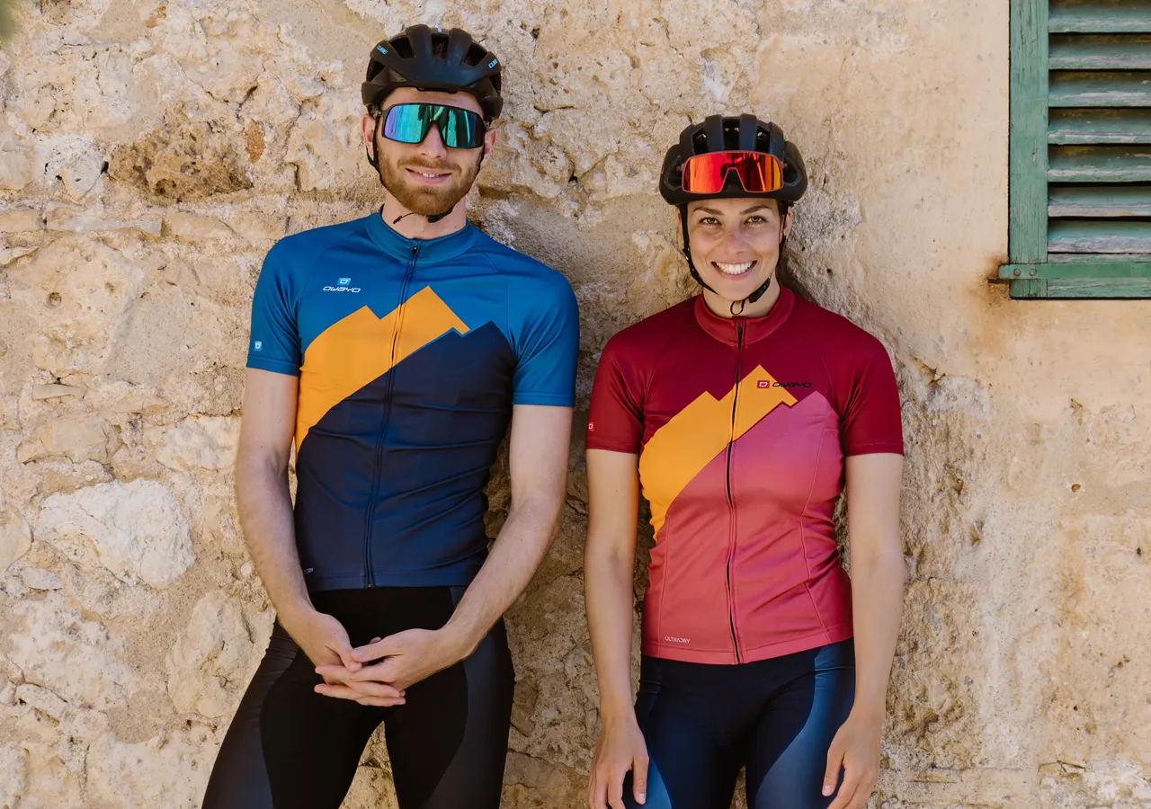 A man and a woman in customized sportswear from owayo, standing in front of a stone wall.